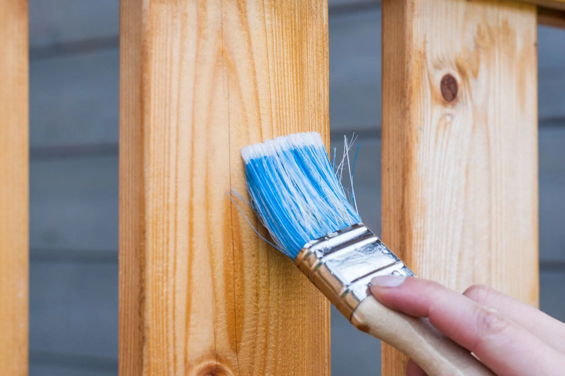 Brush applying timber oil along a wooden board, a key step in deck oiling