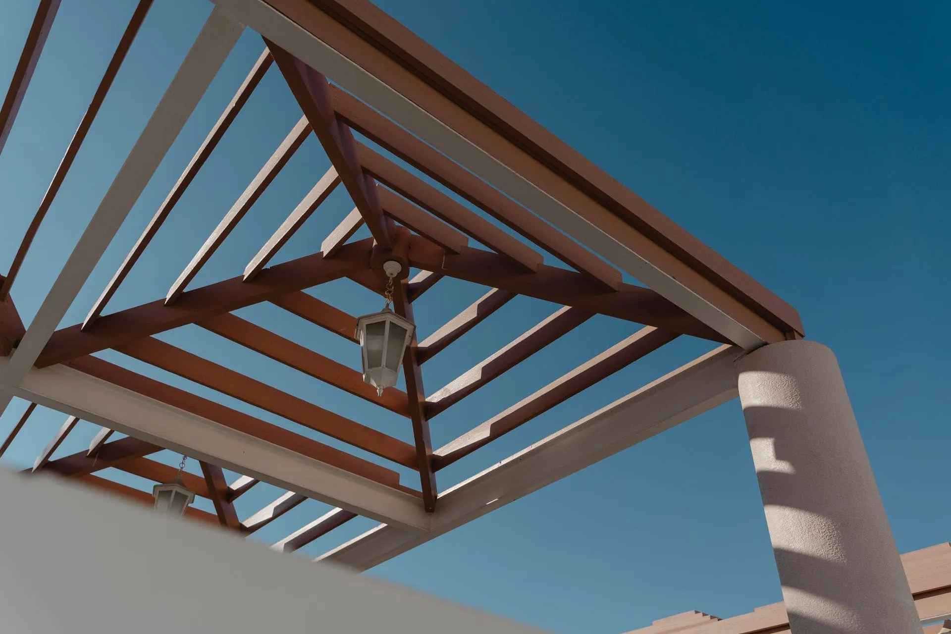 Timber pergola roof framing seen from below against a blue sky, showing pergola roof ideas