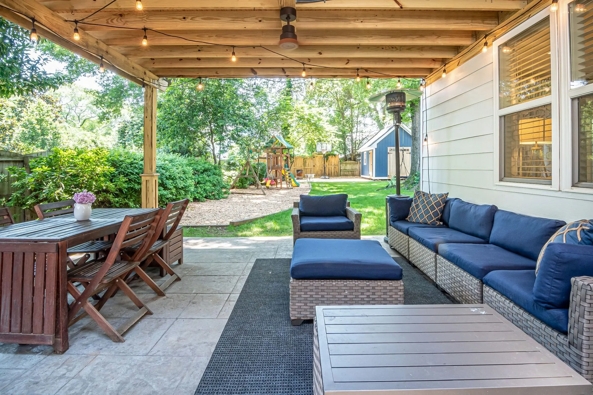 Covered patio with outdoor lounge and dining furniture beside a house