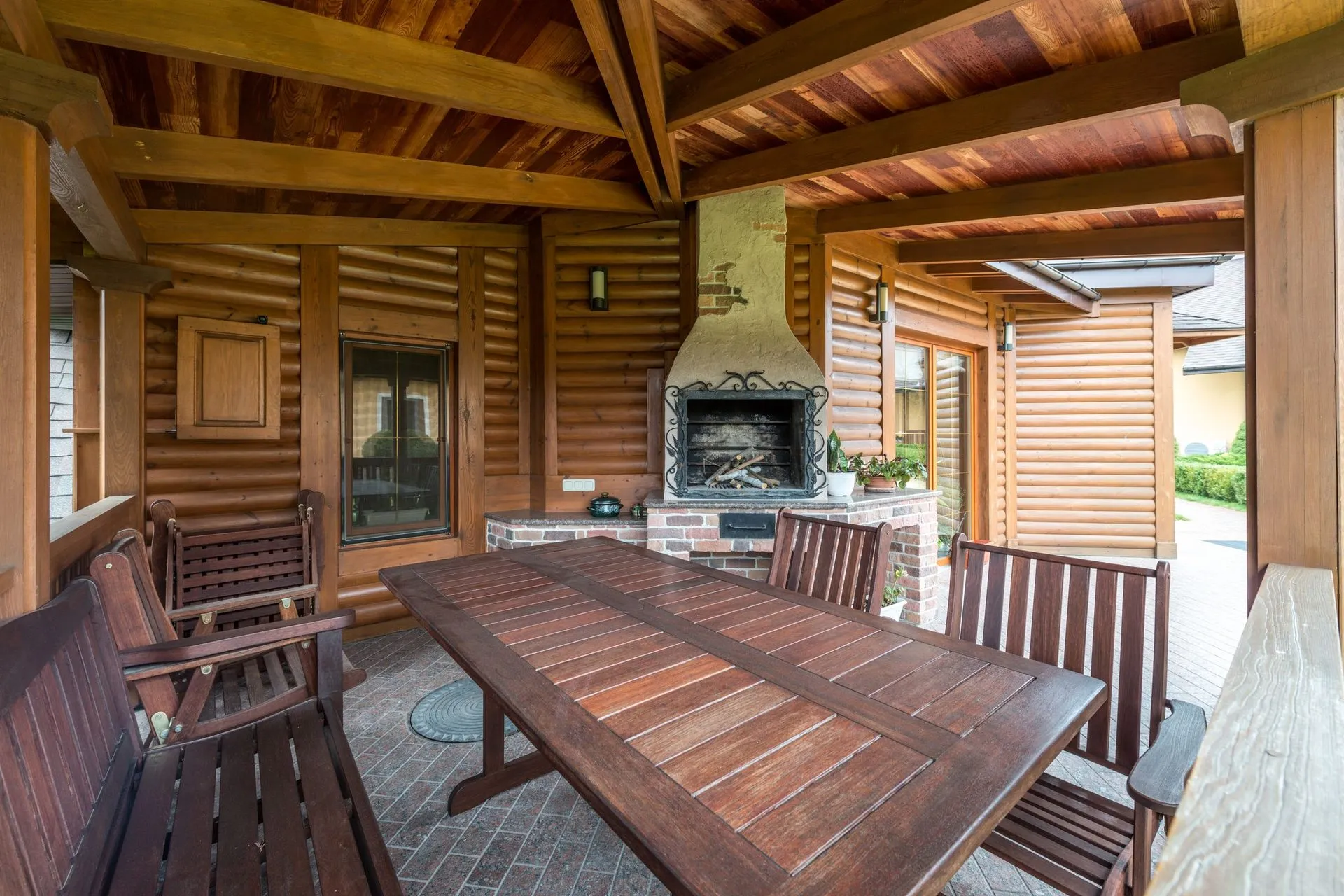 Timber-lined alfresco area with a dining table and an outdoor fireplace