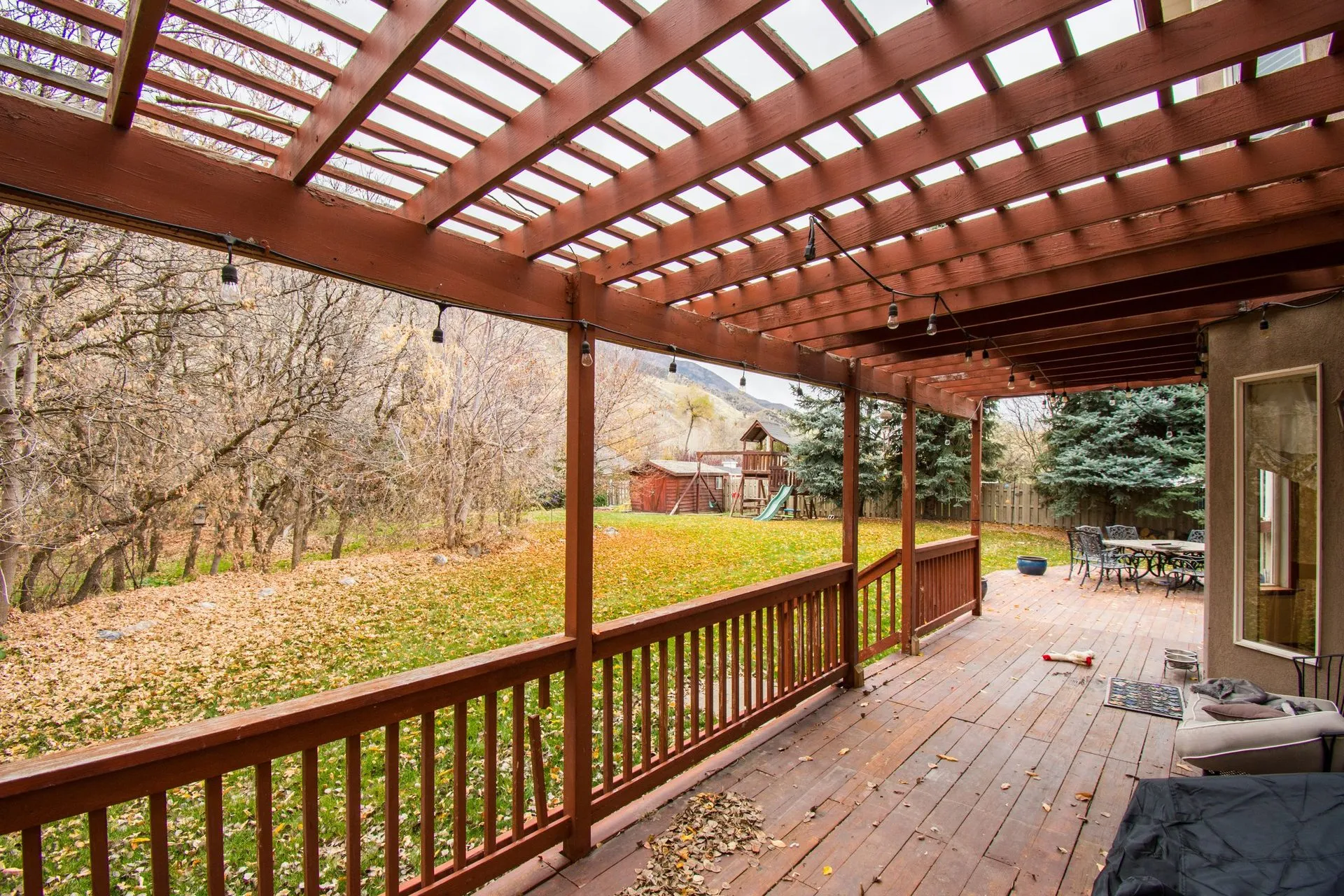 Timber pergola over a raised deck with railings, overlooking a leafy backyard